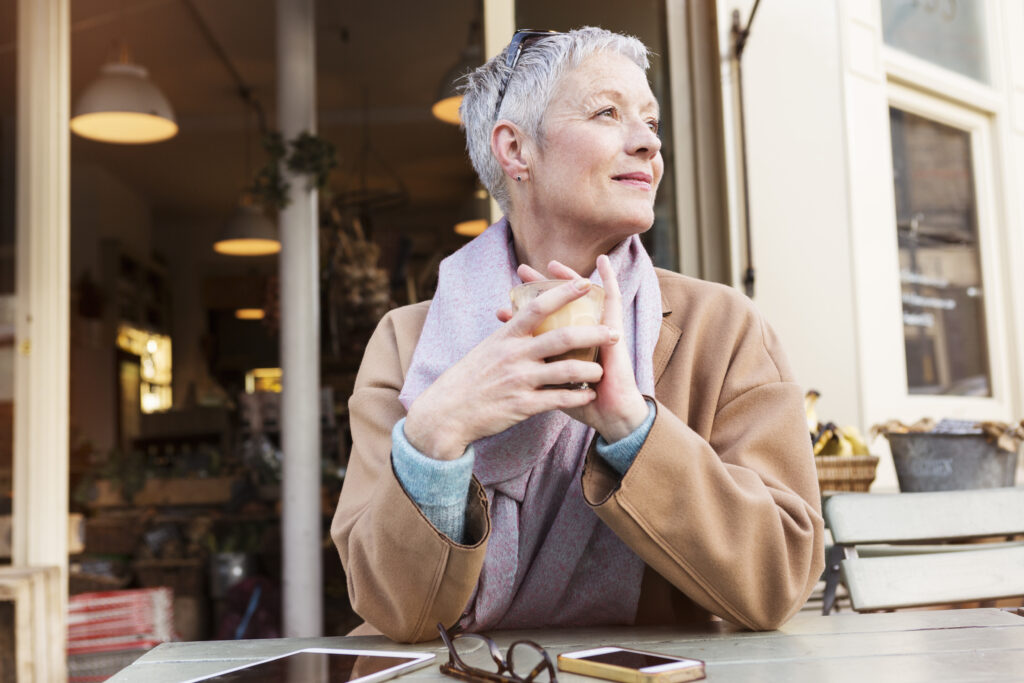 woman with short grey hair drinking a latte.