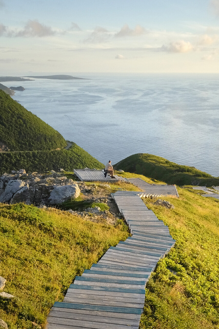man sitting on hill looking out at the ocean