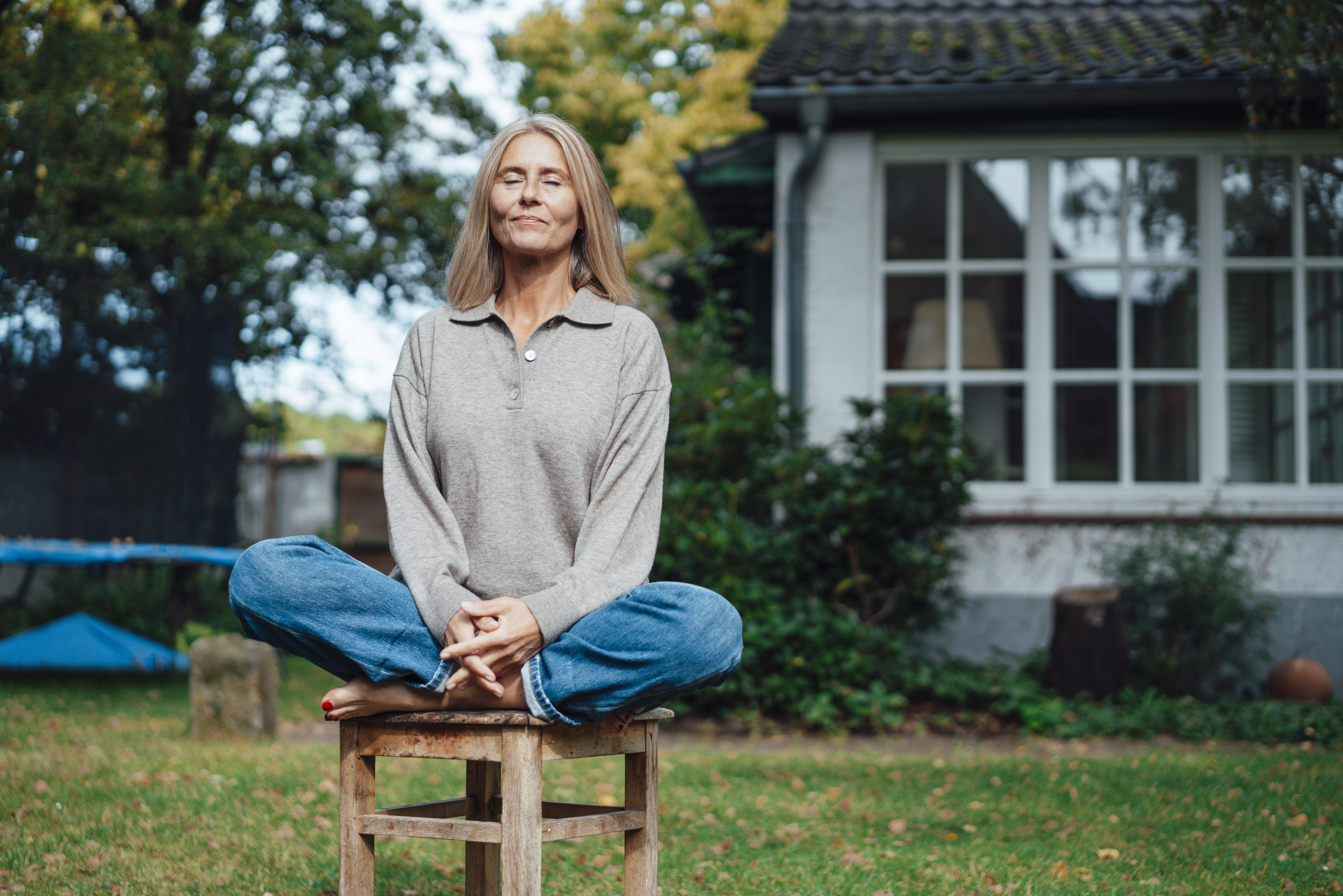Woman practicing yoga on stool at backyard