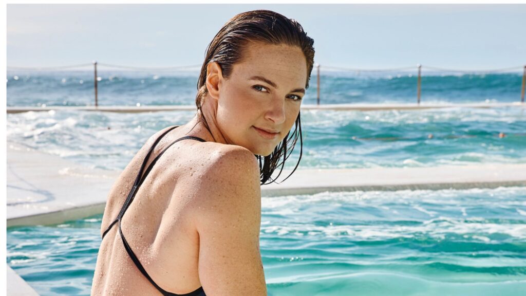 Cate Campbell sitting on the edge of the pool wearing a blue swimsuit