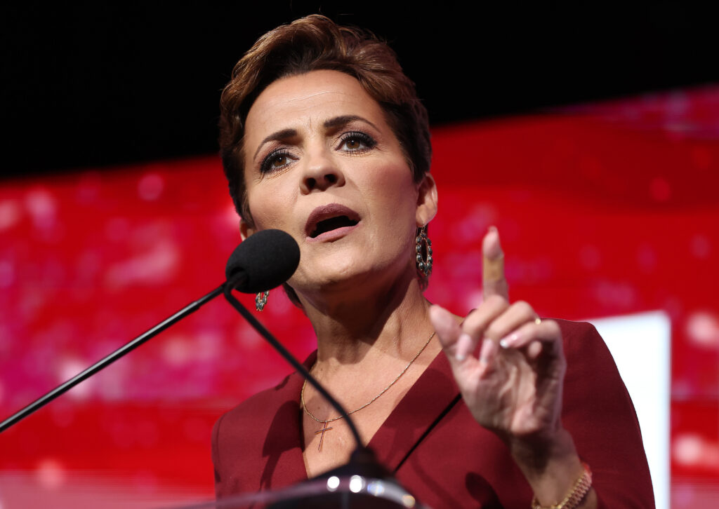 A woman in red speaking at a convention.