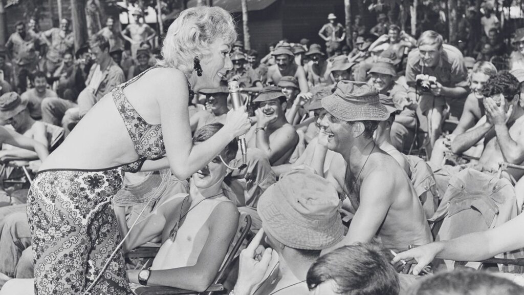 A black and white photo of an Australian entertainer singing to a Vietnam war soldier in the crowd. 