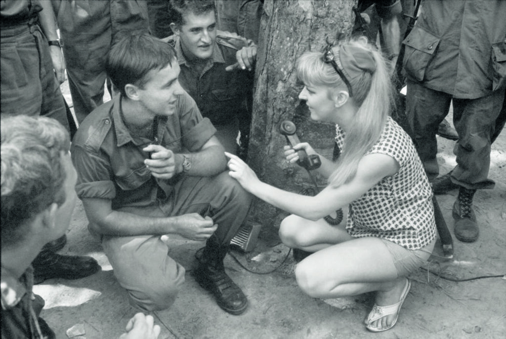 A black and white photo of a female performer talking to a male soldier. 