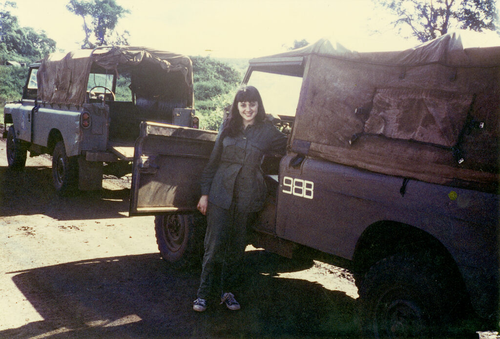 A woman standing in front of a war vehicle. 