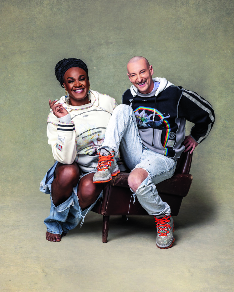 Zaachariaha, in ripped jeans and a white top, and Michael, in ripped jeans and a top decorated with a rainbow, sit side by side.