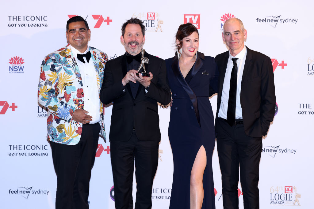 Four people posing at the 64th TV Week Logie Awards, one holding a trophy, standing on the red carpet.