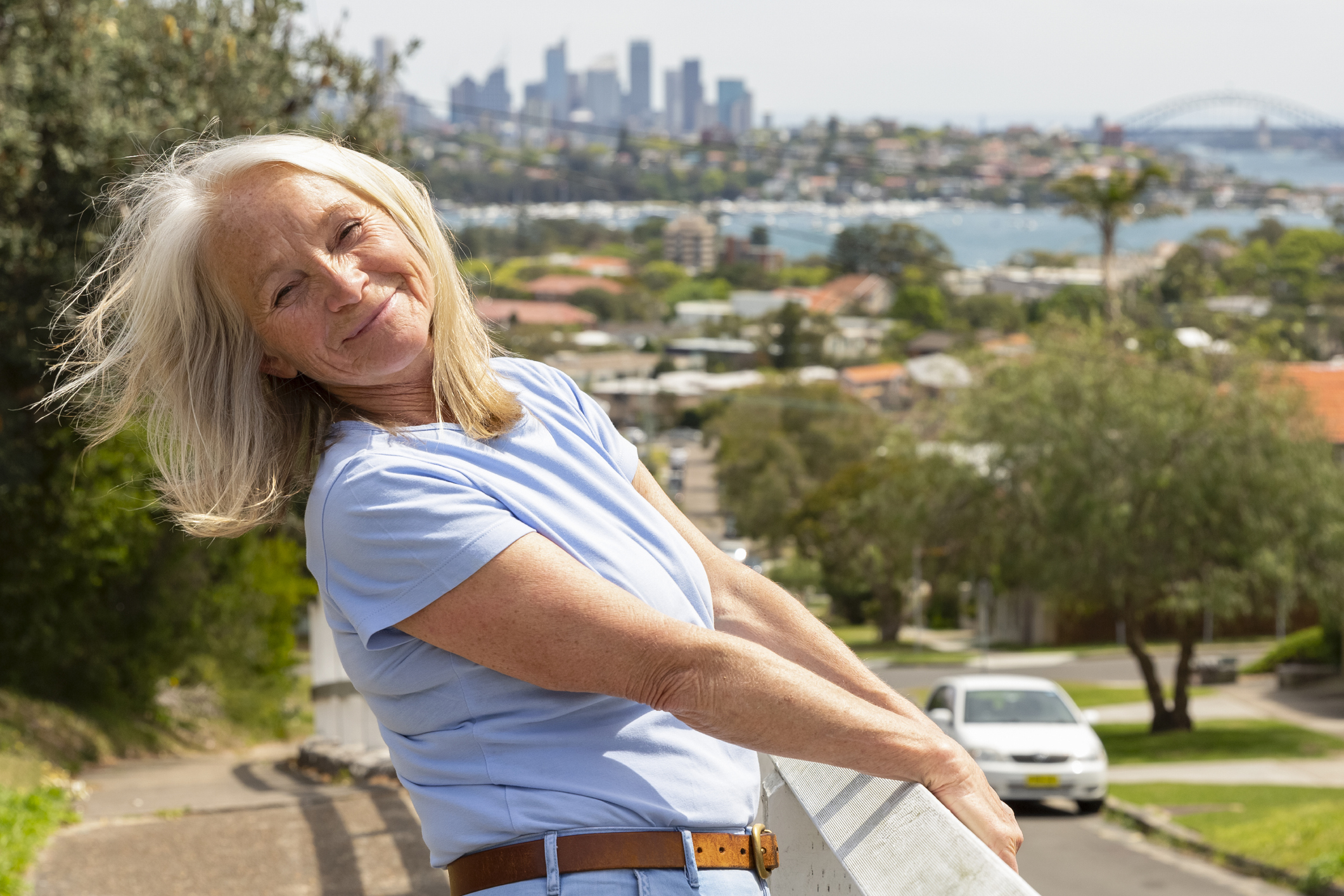 Older woman walking with Sydney in the background. Why Australia has a good life expectancy and better longevity